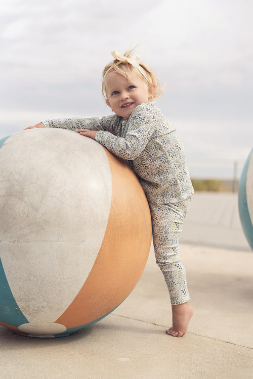 Blue floral girls pajamas by Adee, worn by a smiling toddler outdoors