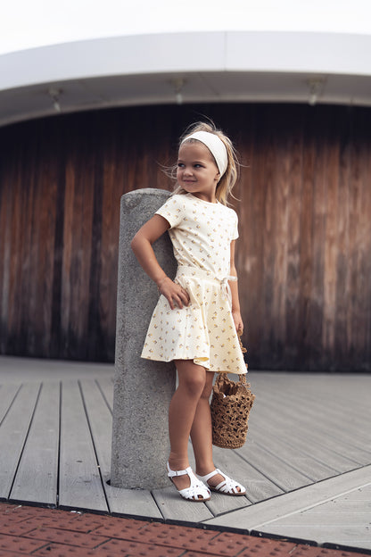 Butter Yellow Tulip T-shirt - Short Sleeve: young girl posing in an ivory patterned dress, headband, sandals.