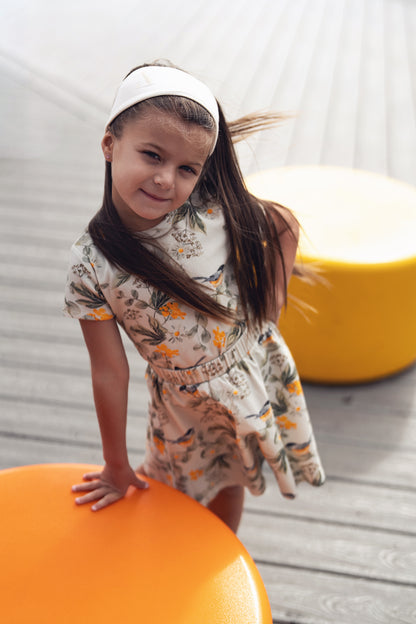 Garden Finch Circle Skirt on a girl in a floral dress with a white headband outdoors.