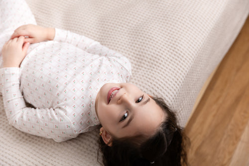 Cherry Window Pajamas for girls in light pink plaid grid, worn by a smiling girl.